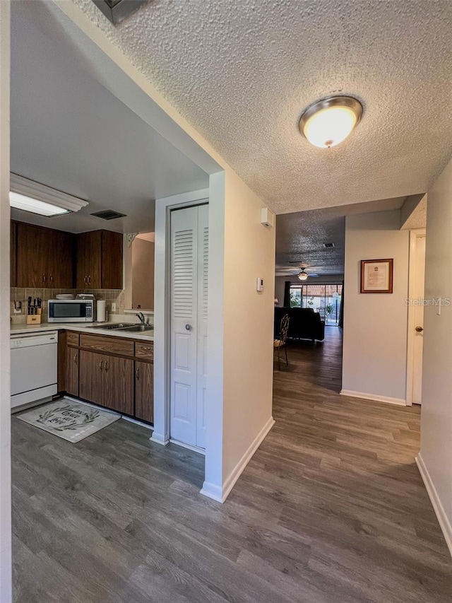 interior space with dark wood-style floors, visible vents, a sink, a textured ceiling, and baseboards