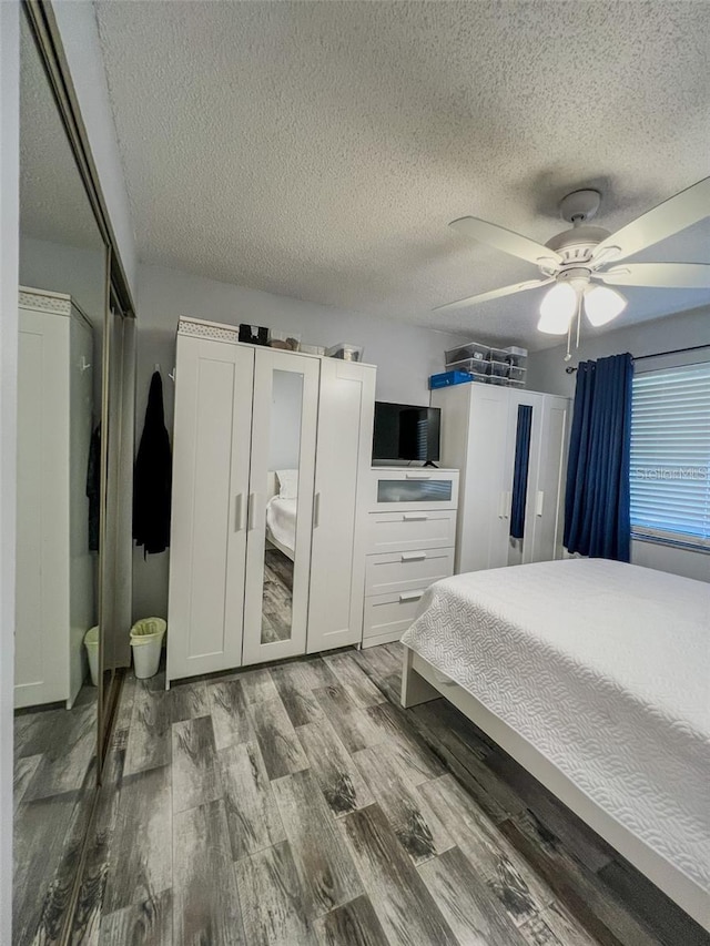 bedroom with ceiling fan, a textured ceiling, and wood finished floors