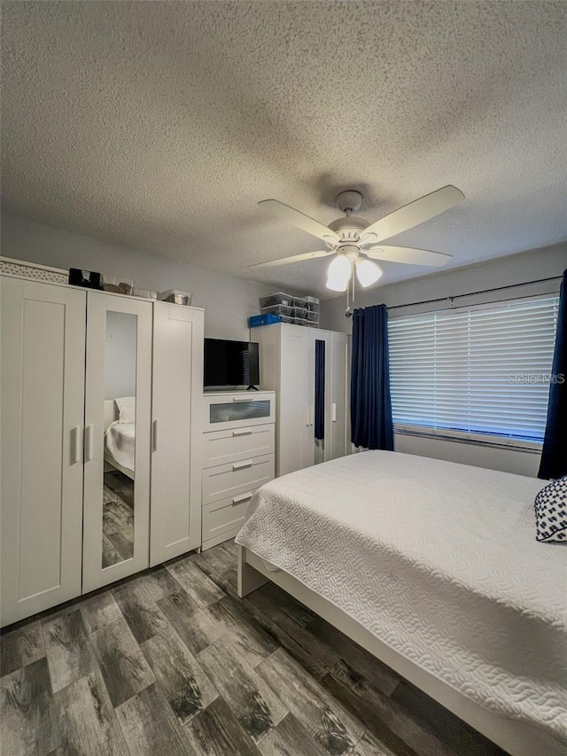 bedroom featuring dark wood-style flooring, ceiling fan, and a textured ceiling