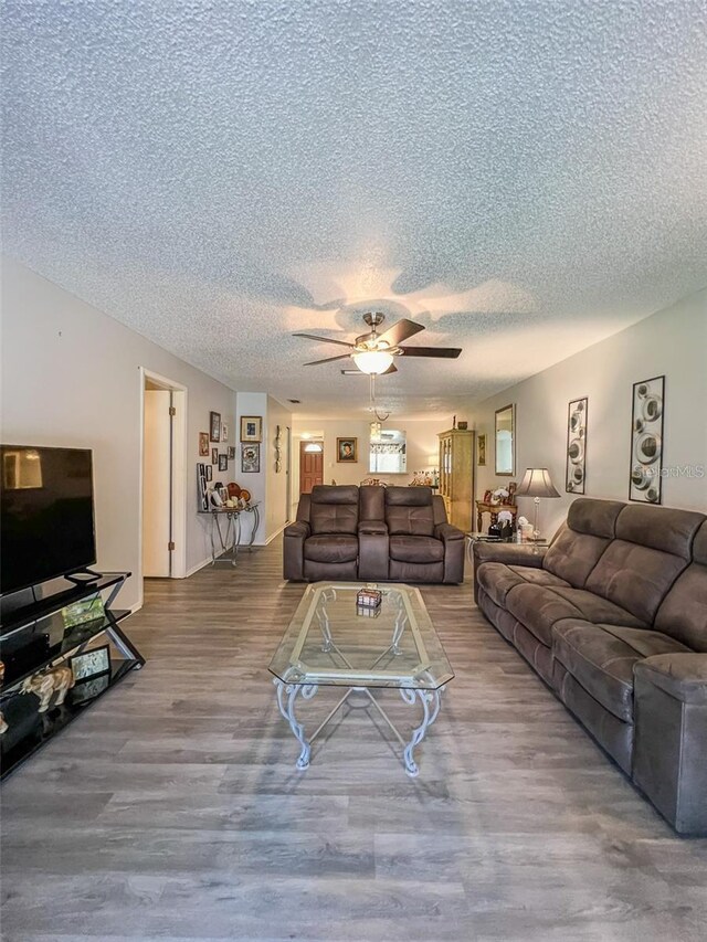 living room with a ceiling fan, a textured ceiling, and wood finished floors