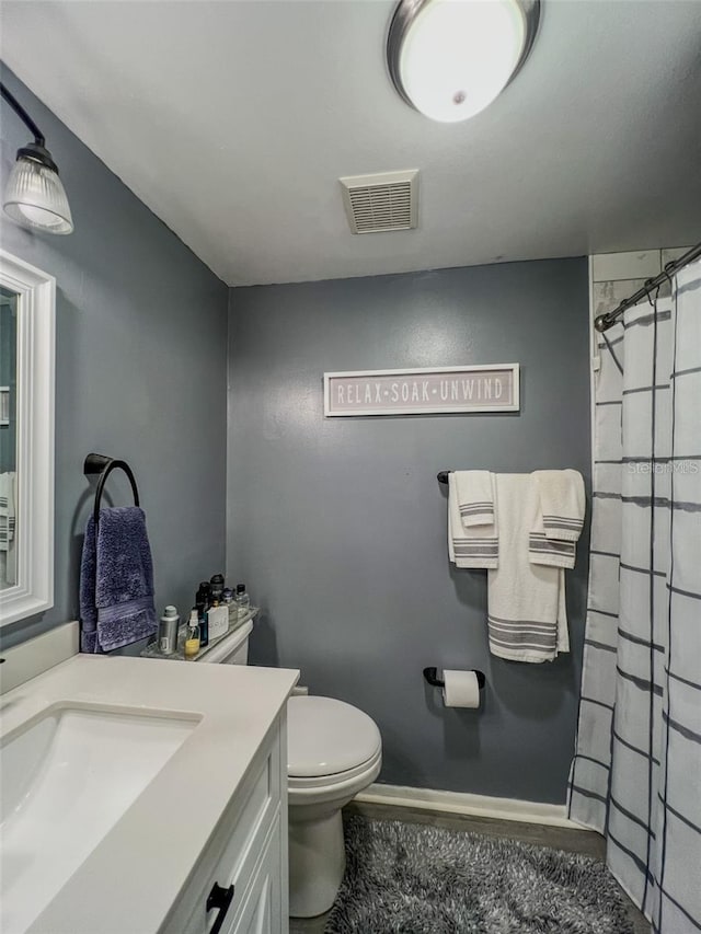 full bath featuring baseboards, visible vents, a shower with shower curtain, toilet, and vanity