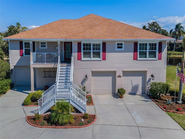 beach home featuring covered porch, a garage, stairs, driveway, and stucco siding