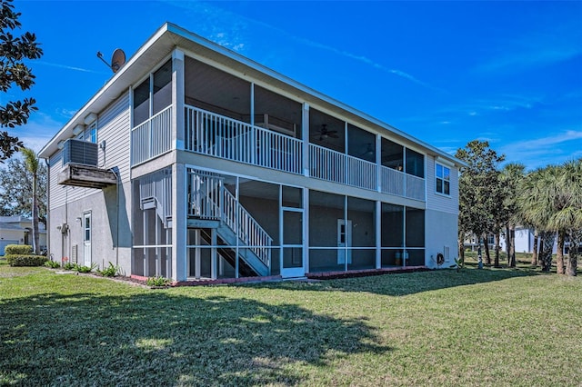 back of house featuring a ceiling fan, a sunroom, a yard, and stairway