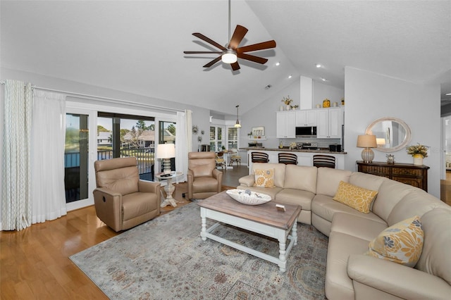 living area featuring high vaulted ceiling, a ceiling fan, and light wood-style floors