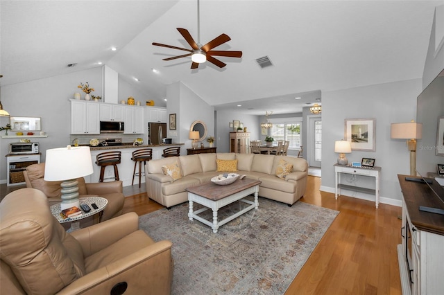 living room with visible vents, high vaulted ceiling, light wood-type flooring, baseboards, and ceiling fan with notable chandelier