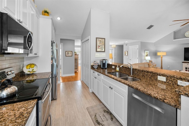 kitchen featuring a sink, stainless steel appliances, light wood-style floors, white cabinetry, and backsplash