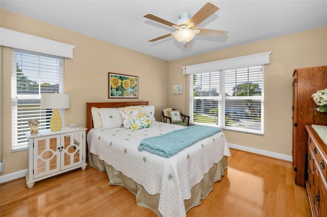 bedroom with light wood finished floors, baseboards, and a ceiling fan