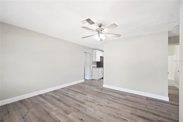 unfurnished room with visible vents, light wood-style flooring, ceiling fan, a textured ceiling, and baseboards