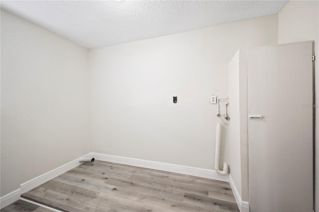 washroom featuring laundry area, a textured ceiling, baseboards, and wood finished floors