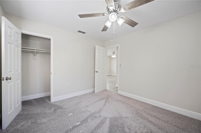 unfurnished bedroom with baseboards, visible vents, a textured ceiling, carpet floors, and a closet