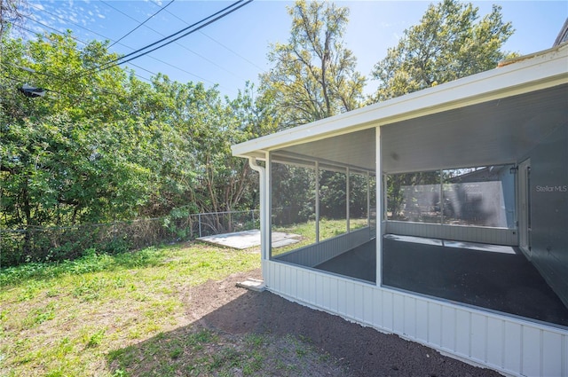 view of yard with a carport, fence, and a sunroom