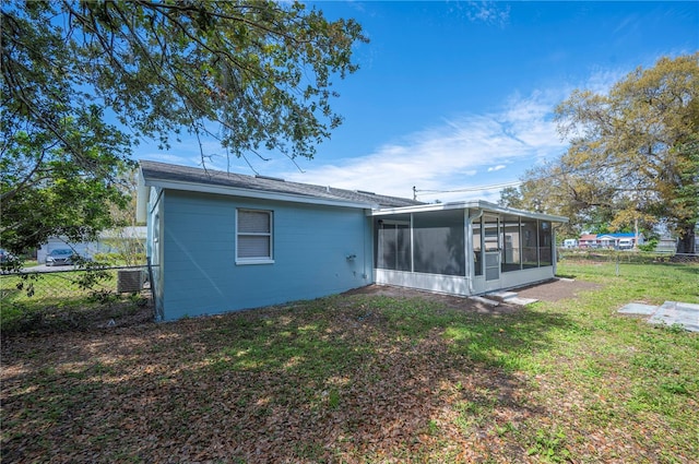 rear view of property with a sunroom, fence, and a lawn