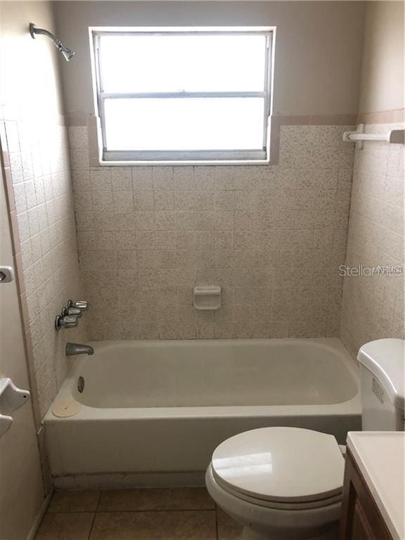 bathroom featuring vanity, shower / bathing tub combination, tile patterned floors, toilet, and tile walls