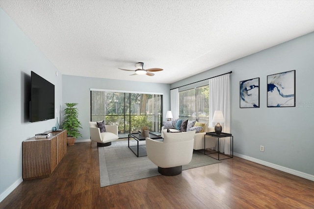 living area with ceiling fan, baseboards, a textured ceiling, and wood finished floors