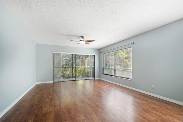 spare room with a wealth of natural light, baseboards, ceiling fan, and wood finished floors