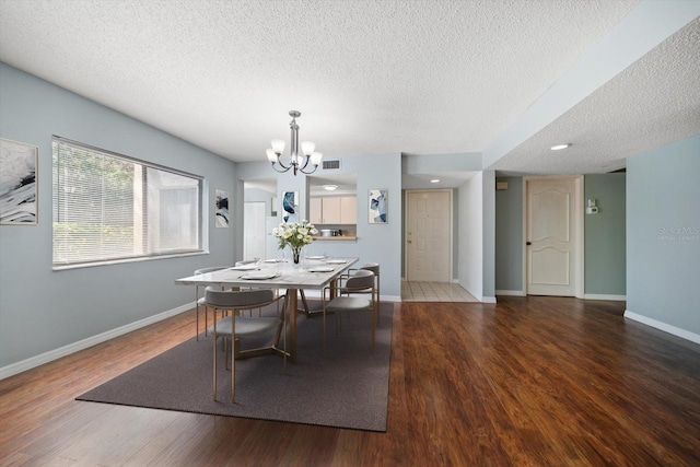 dining room with visible vents, a textured ceiling, wood finished floors, an inviting chandelier, and baseboards