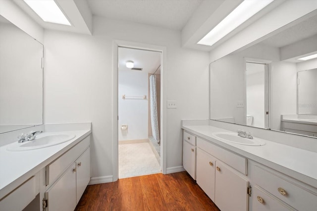 full bathroom with wood finished floors, two vanities, and a sink