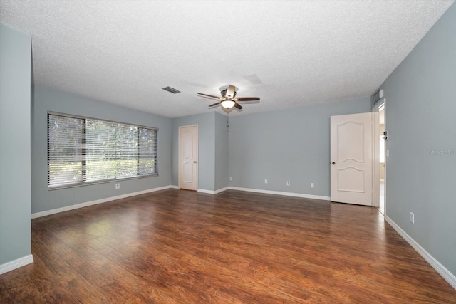 empty room featuring a ceiling fan, visible vents, baseboards, dark wood-type flooring, and a textured ceiling