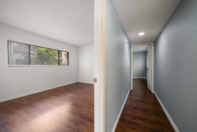 hallway featuring baseboards, a textured ceiling, and wood finished floors