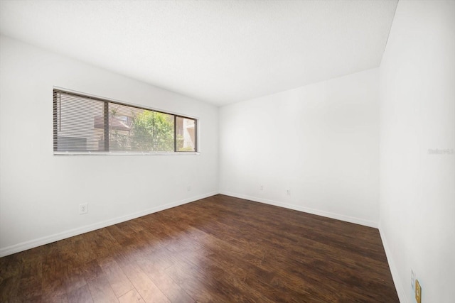 empty room featuring baseboards and dark wood-style flooring