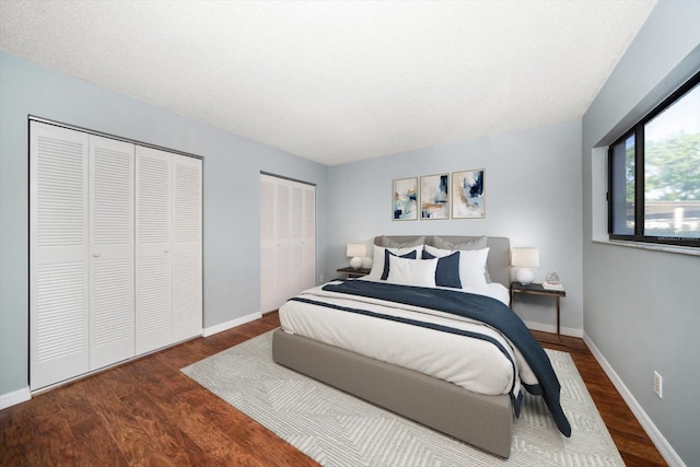 bedroom with baseboards, multiple closets, and wood finished floors