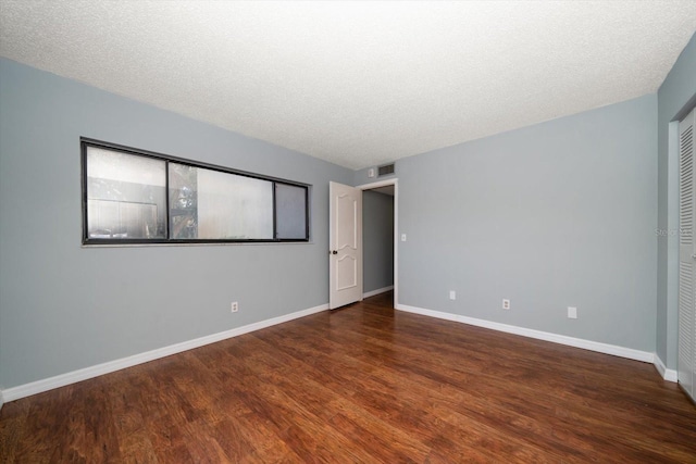 unfurnished bedroom featuring wood finished floors, baseboards, and a textured ceiling