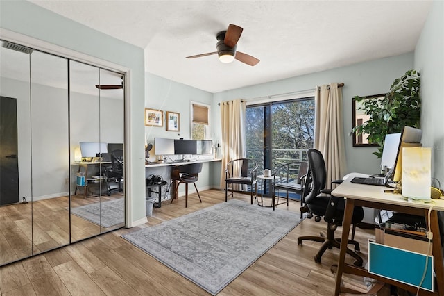 office space featuring baseboards, a ceiling fan, and wood finished floors