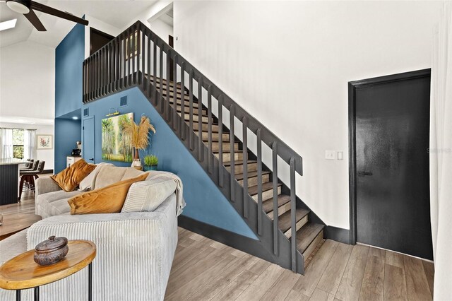 staircase featuring high vaulted ceiling and wood finished floors