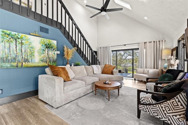 living room with stairs, wood finished floors, visible vents, and a ceiling fan