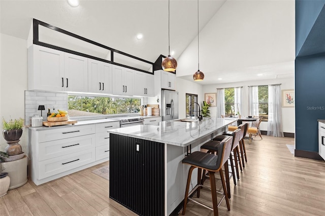 kitchen with white cabinets, a sink, light wood finished floors, and stainless steel fridge with ice dispenser