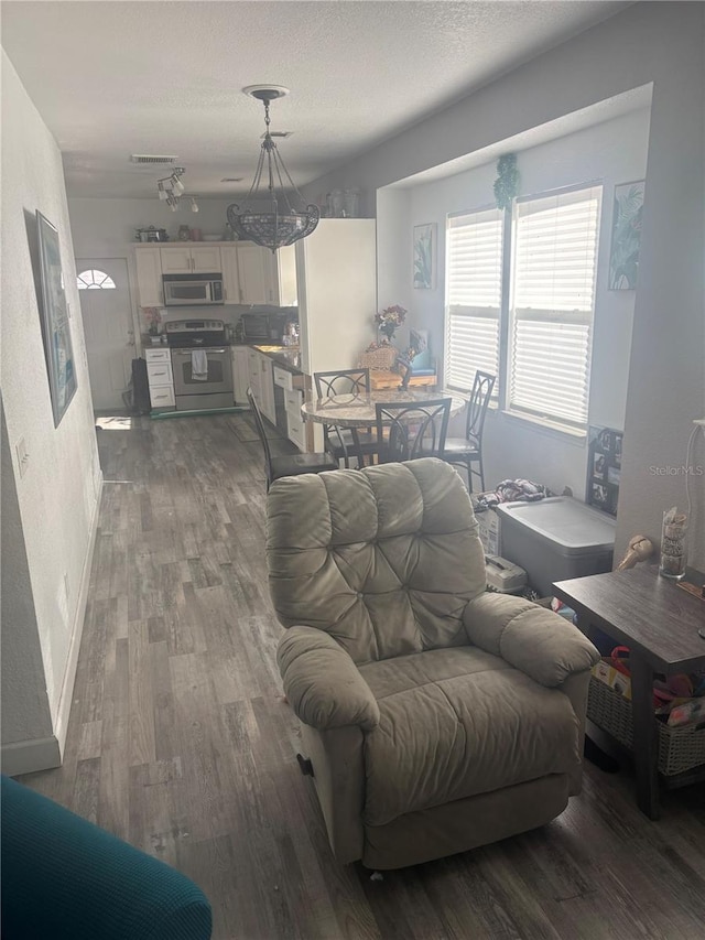 living room featuring a textured ceiling, wood finished floors, visible vents, and baseboards