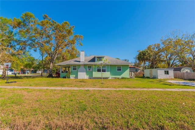 view of front of property featuring a chimney, a front lawn, and fence