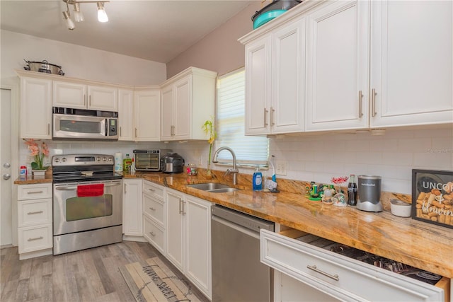 313 Jefferson Ave S, Oldsmar, FL 34677 - kitchen with light wood finished floors, tasteful backsplash, white cabinets, stainless steel appliances, and a sink