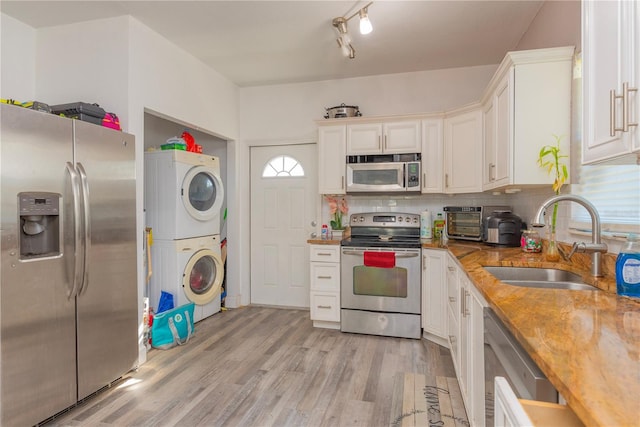 313 Jefferson Ave S, Oldsmar, FL 34677 - kitchen featuring a sink, decorative backsplash, stacked washer and clothes dryer, appliances with stainless steel finishes, and white cabinetry