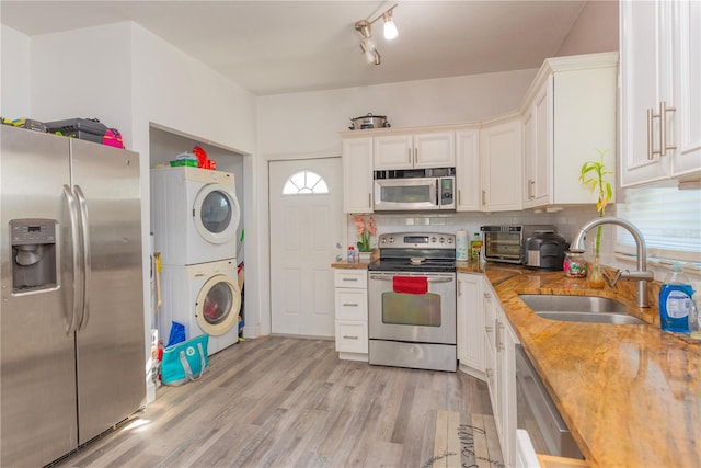 313 Jefferson Ave S, Oldsmar, FL 34677 - kitchen with backsplash, white cabinetry, stacked washer and clothes dryer, stainless steel appliances, and a sink