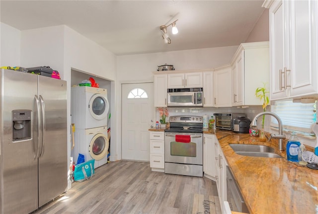 313 Jefferson Ave S, Oldsmar, FL 34677 - kitchen featuring a sink, decorative backsplash, stacked washer and dryer, white cabinets, and appliances with stainless steel finishes