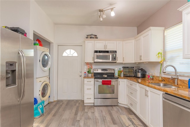 313 Jefferson Ave S, Oldsmar, FL 34677 - kitchen with stacked washing maching and dryer, light wood-style flooring, a sink, decorative backsplash, and appliances with stainless steel finishes