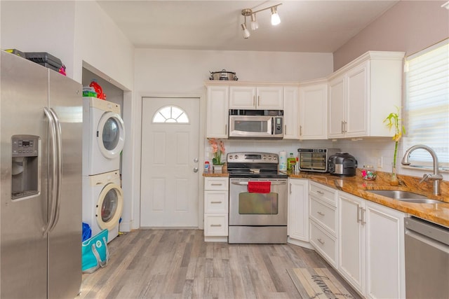313 Jefferson Ave S, Oldsmar, FL 34677 - kitchen featuring a sink, stacked washer and dryer, light wood-style floors, appliances with stainless steel finishes, and tasteful backsplash