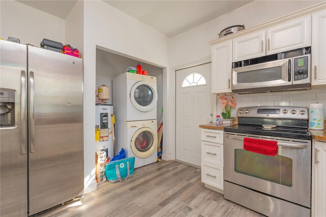 313 Jefferson Ave S, Oldsmar, FL 34677 - kitchen featuring stainless steel appliances, stacked washer / drying machine, white cabinets, light wood finished floors, and decorative backsplash