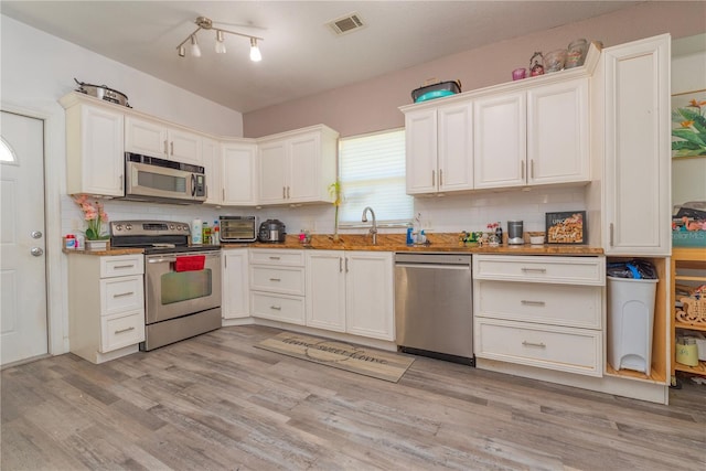313 Jefferson Ave S, Oldsmar, FL 34677 - kitchen featuring visible vents, a sink, light wood-style floors, appliances with stainless steel finishes, and backsplash
