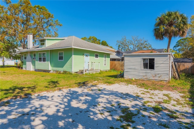 313 Jefferson Ave S, Oldsmar, FL 34677 - rear view of property with an outbuilding, a lawn, a chimney, and fence