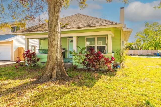 313 Jefferson Ave S, Oldsmar, FL 34677 - view of front facade featuring fence, covered porch, a shingled roof, a chimney, and a front lawn
