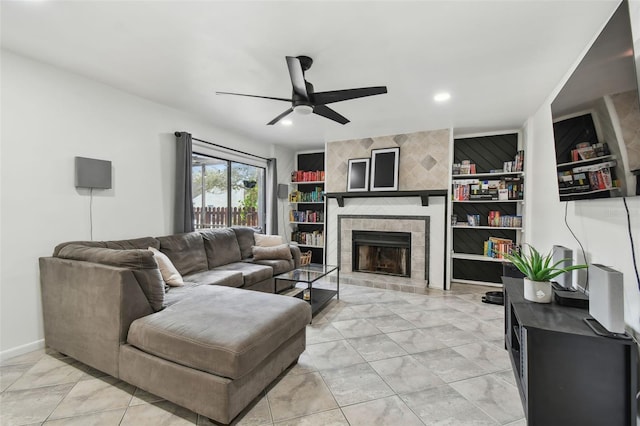 living room with built in shelves, recessed lighting, ceiling fan, a tile fireplace, and baseboards