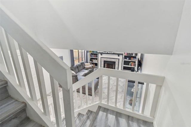 stairway with vaulted ceiling, a brick fireplace, and wood finished floors