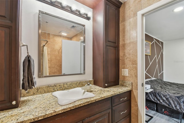 full bath featuring a shower with curtain, visible vents, vanity, and tile walls