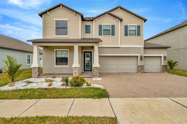 view of front facade with covered porch, stone siding, decorative driveway, and stucco siding