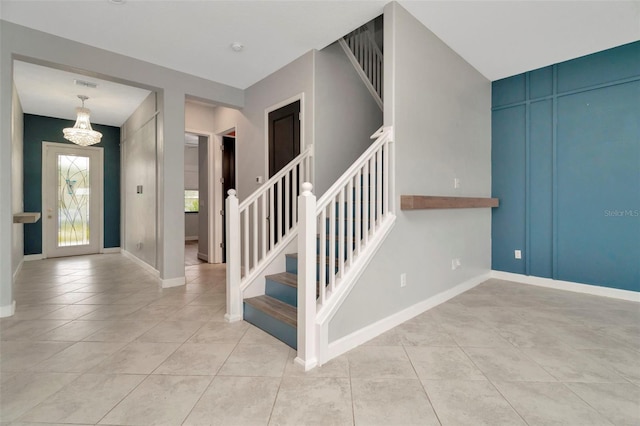 stairway featuring a notable chandelier, baseboards, and tile patterned floors