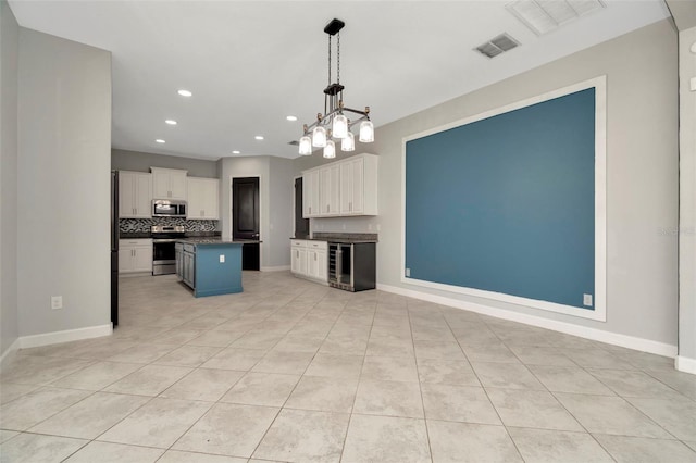 kitchen featuring visible vents, dark countertops, wine cooler, appliances with stainless steel finishes, and white cabinetry