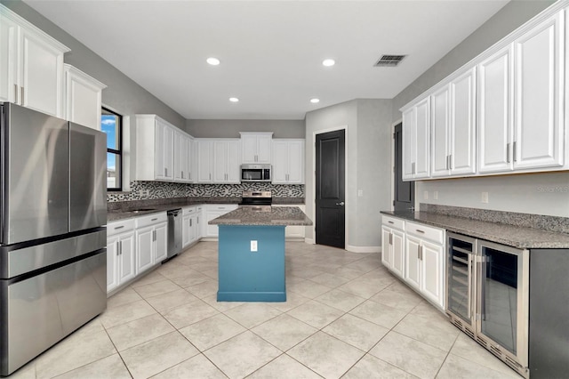 kitchen with white cabinets, light tile patterned floors, beverage cooler, and stainless steel appliances