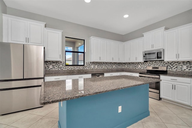 kitchen featuring light tile patterned floors, a kitchen island, white cabinetry, appliances with stainless steel finishes, and tasteful backsplash